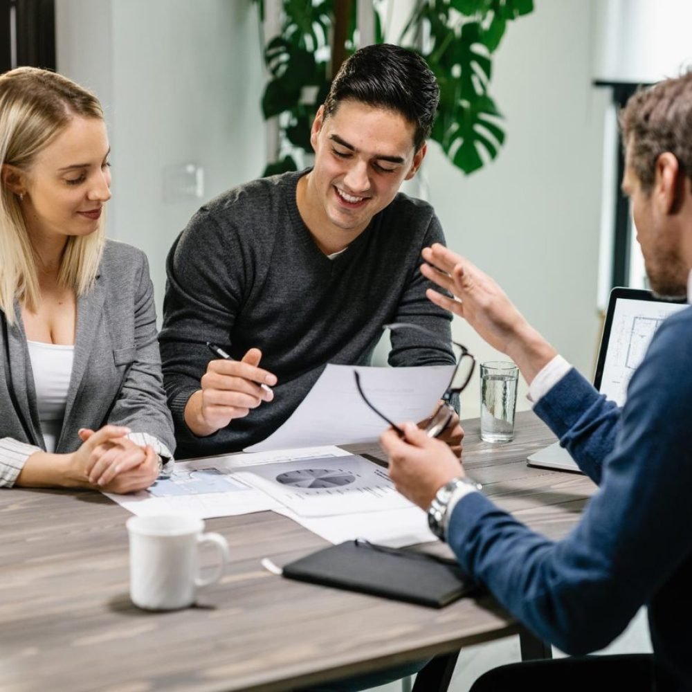 young-happy-couple-reading-terms-mortgage-documents-while-having-meeting-with-real-estate-agent-home-focus-is-young-man young-happy-couple-reading-terms-mortgage-documents-while-having-meeting-with-real-estate-agent-home-focus-is-young-man